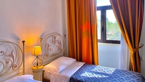 A bedroom with a bed, a nightstand with a lamp, and curtains.