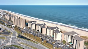 Een kustgebied met woonwijken, hoge gebouwen, een strand en een weg met parkeerplaatsen.