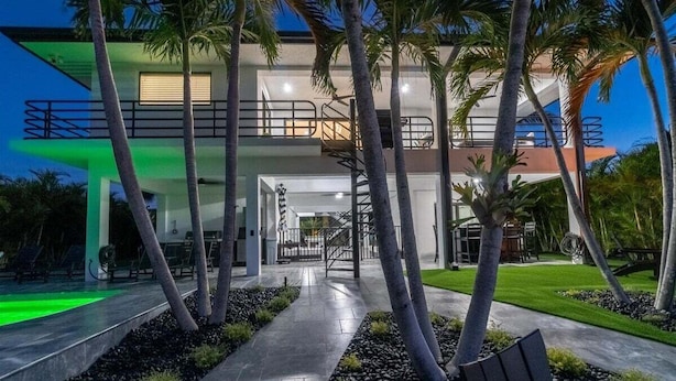 Une maison moderne à deux étages, dotée d’un balcon, d’un escalier et d’un jardin bien entretenu.