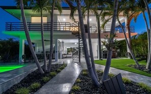 Een modern huis met twee verdiepingen, een balkon, een trap en een verzorgde tuin.