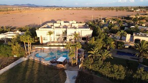 Un resort con una piscina grande, palmeras y un paisaje desértico al fondo.