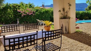 Terassi, jossa on pöytä ja tuoleja, ja jota ympäröi vehreys sekä josta avautuu näkymä vuorille.