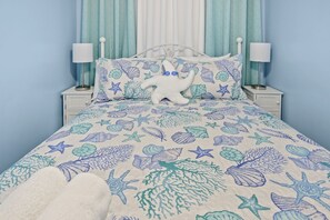 A bed with a blue and white sea-themed bedspread, white pillows, and a white starfish decoration. - A203 at The Myrtle Beach Resort (Myrtle Beach)