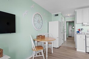 A kitchen with a dining table, chairs, a refrigerator, and a television on the wall. - A203 at The Myrtle Beach Resort (Myrtle Beach)