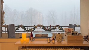 A cozy room with a view of a snowy landscape, a wooden table with candles, a Christmas wreath, and a Christmas tree. - Ihr Perfekten Rückzugsort, um die Schönheit des Oberharzes zu Entdecken (Sankt Andreasberg)