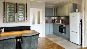 A modern kitchen with grey cabinets, a white refrigerator, and a wooden dining table with grey chairs. - Ihr Perfekten Rückzugsort, um die Schönheit des Oberharzes zu Entdecken (Sankt Andreasberg)