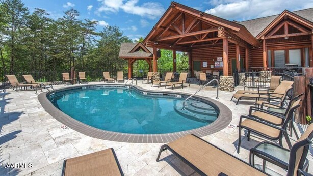 Un espace piscine avec des chaises longues et, au fond, un bâtiment en bois.