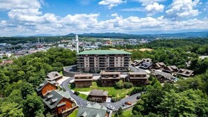 Un hôtel à plusieurs étages doté d’une cour intérieure, entouré d’une végétation luxuriante et ayant une chaîne de montagnes en toile de fond.