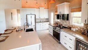 A spacious kitchen with white cabinets, a large island, and pendant lighting. - Paradise Cove 3 Bedroom Home (Gregory Town)