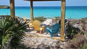 A wooden gazebo with two chairs, overlooking a clear blue sea. - Paradise Cove 3 Bedroom Home (Gregory Town)