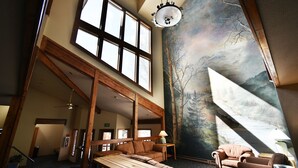 A spacious room with high ceilings, large windows, and a mural of a forest scene. - On River Trail! Pool, Hot Tub, Elevator! Walk to Festivals, Dining, Shops (Keystone)