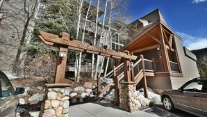 A wooden entrance gate with the name "Snowdance Manor" and a stone staircase leading to a wooden building with a sloped roof. - On River Trail! Pool, Hot Tub, Elevator! Walk to Festivals, Dining, Shops (Keystone)