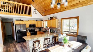 A spacious kitchen with wooden cabinets, a large island, and a dining area with white chairs.