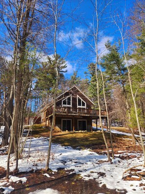 A cabin with a wooden deck and large windows, surrounded by trees and snow. - Beautiful private Tainter Lake Retreat in Western WI. Sleeps 10 (Menomonie)