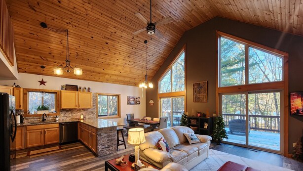 A spacious living area with a large window, a cozy fireplace, and a wooden ceiling.