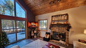 A cozy living room with a fireplace, large windows, and a deck.