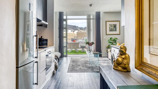 Una cucina moderna con frigorifero Bosch integrato, una zona pranzo con tavolo e sedie, e vista sulla città attraverso ampie finestre.