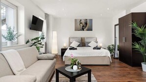 Un dormitorio moderno con una cama, un sofá, un televisor y un cuadro en la pared.