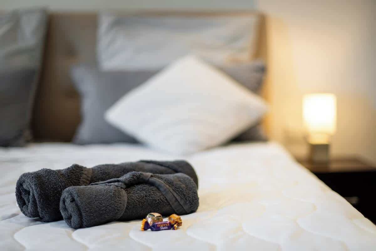 Ein ordentlich bezogenes Bett mit einer weißen Matratze und dunkelgrauen Kissen.