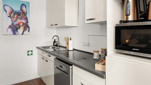 Una cocina moderna con armarios blancos, encimera negra, electrodomésticos de acero inoxidable y un cuadro de un perro.
