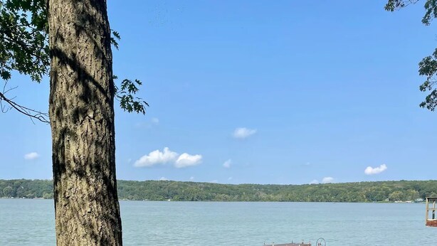 Eine Uferlandschaft mit Picknicktisch, Stühlen und einer Anlegestelle.