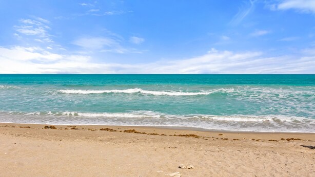 Ein Strand mit klarem türkisblauem Wasser und einem sandigen Ufer.