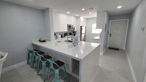 Eine moderne Küche mit einer zentralen Kochinsel, Barhocker und einem Kühlschrank.