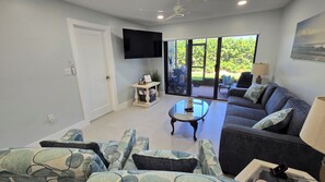 A living room with a sofa, a coffee table, and a television. - Promotion: Updated ground floor unit just steps away from the beach (Jensen Beach)