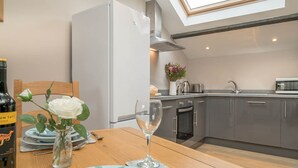 A modern kitchen with grey cabinets, a built-in oven, and a stainless steel sink. - Romantic One Bedroom Cottage Walking Distance From The Beach | Felin-Pennarth (Clynnog)