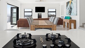 Una sala de estar moderna con una gran mesa de comedor de madera, una chimenea y un televisor montado en la pared.