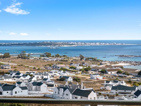 Zona residencial costera con casas blancas, cielo azul despejado y vista al mar.