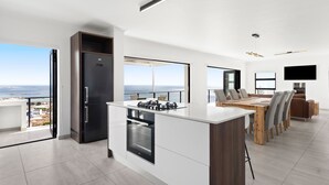 Una cocina moderna con una isla central, un comedor con vistas y un televisor grande montado en la pared.