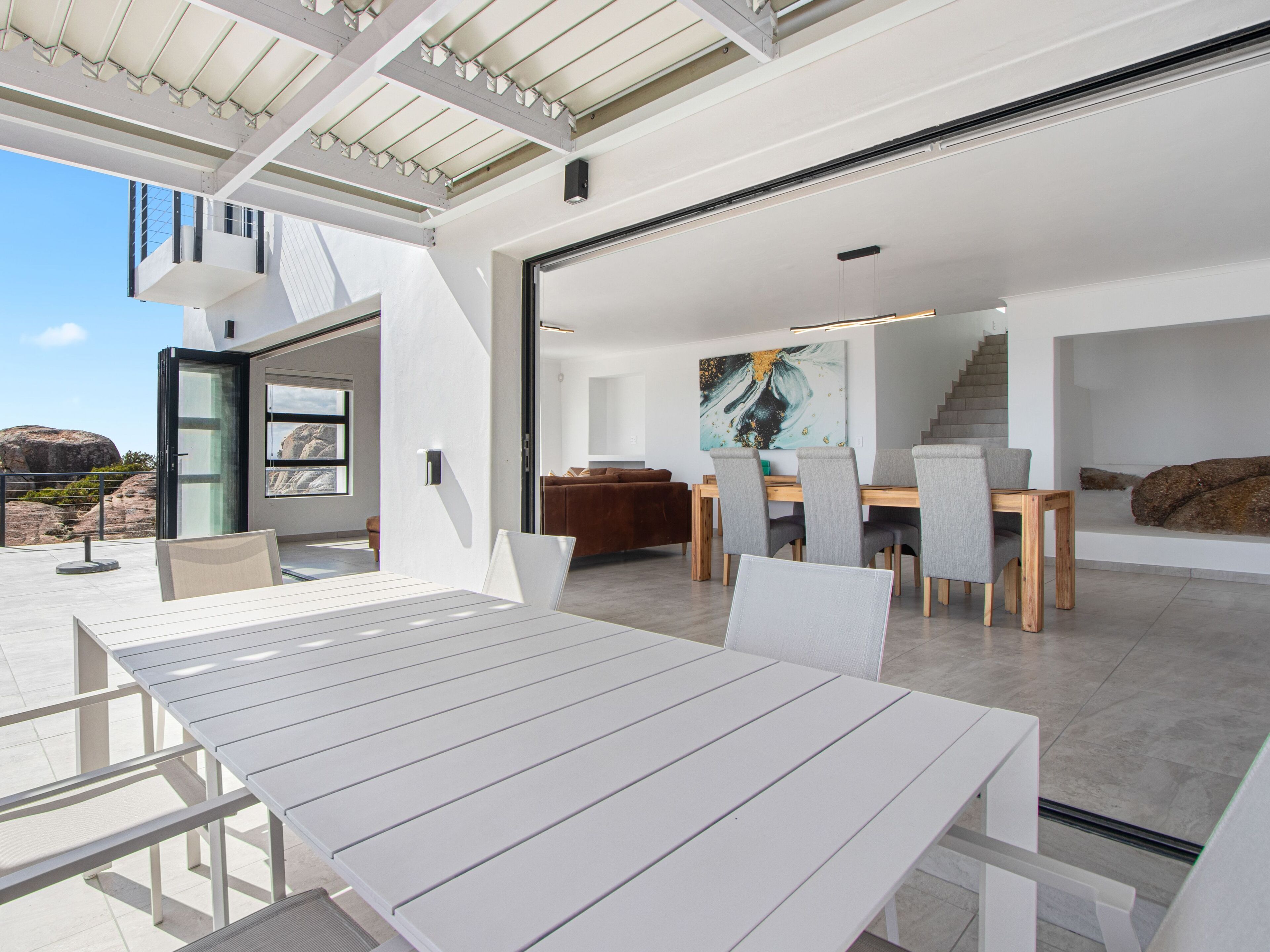 A modern interior with a dining area, a staircase, and a view of the outdoors.