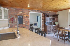 A kitchen with a marble countertop, a brick wall, and wooden ceiling.