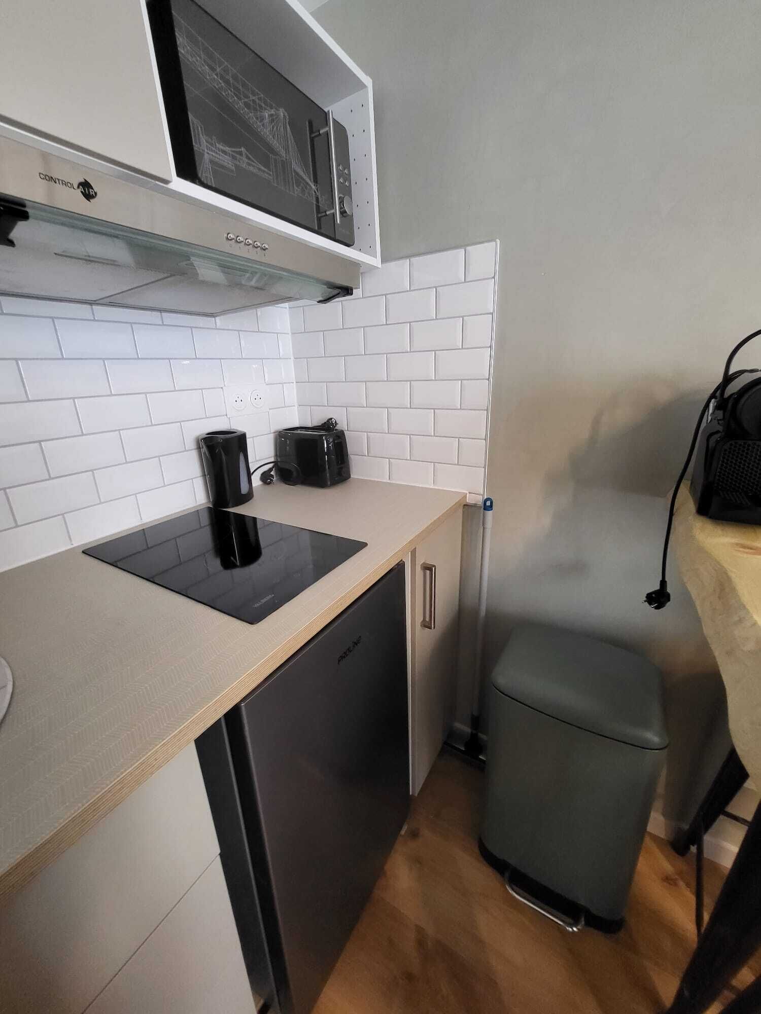 Una kitchenette compacta con microondas, tostadora y cafetera sobre una encimera de tonos claros.