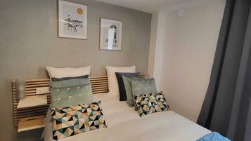 Un dormitorio con cama, almohadas, una mesita de noche y decoración en la pared.