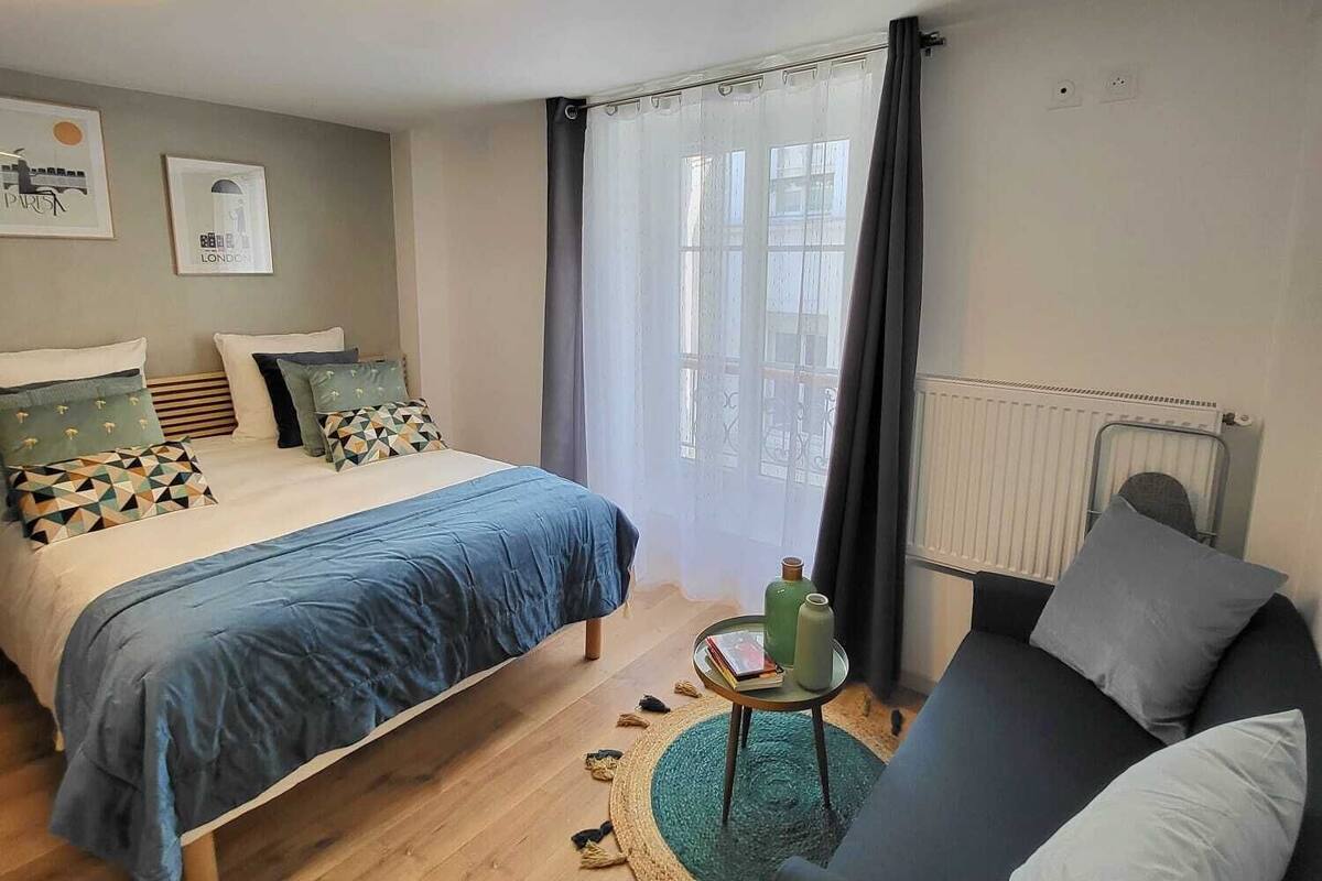 Une chambre moderne avec un lit, un canapé, une petite table et un radiateur.