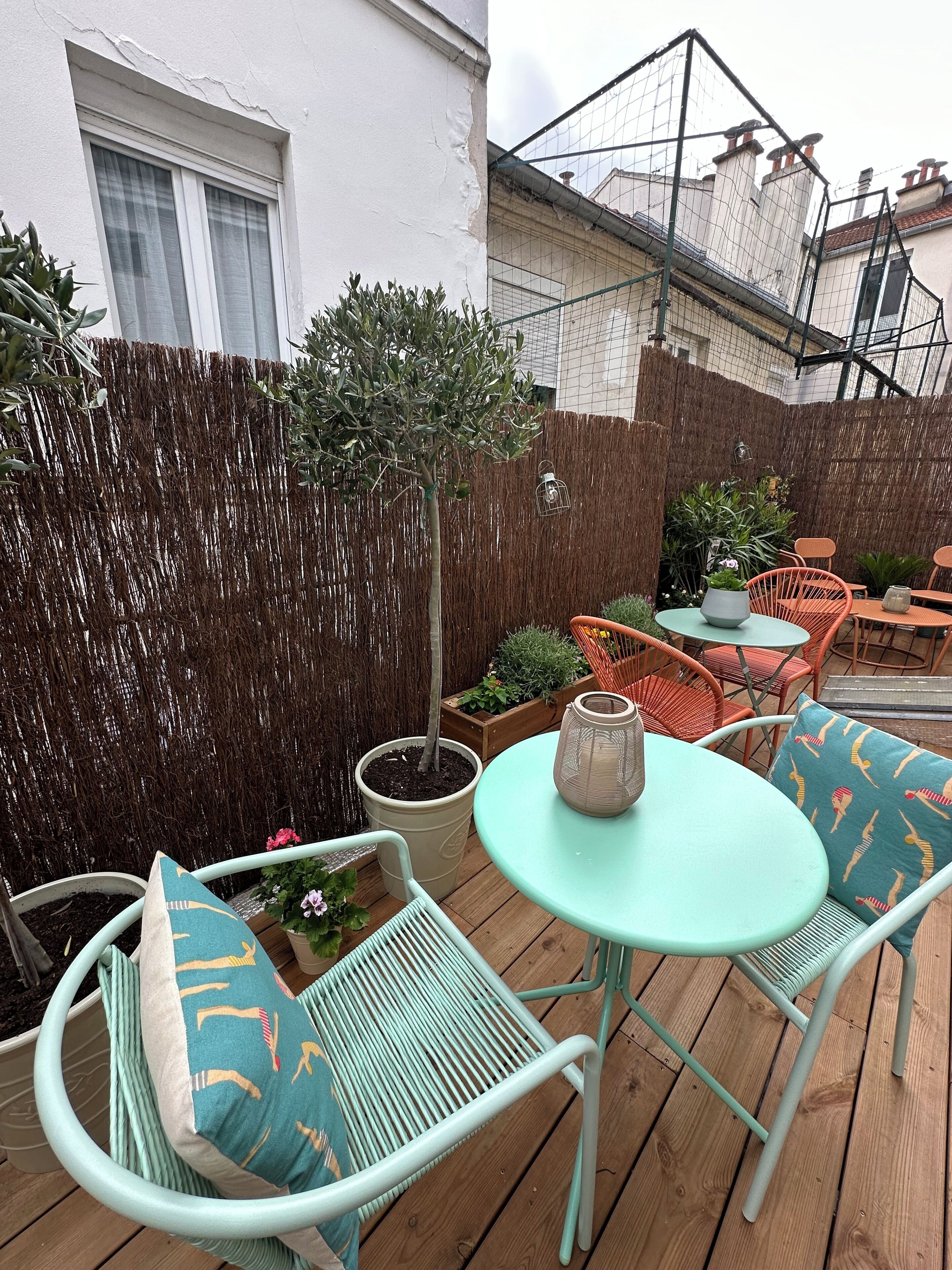 A patio with outdoor furniture, a small tree, and a decorative fence.