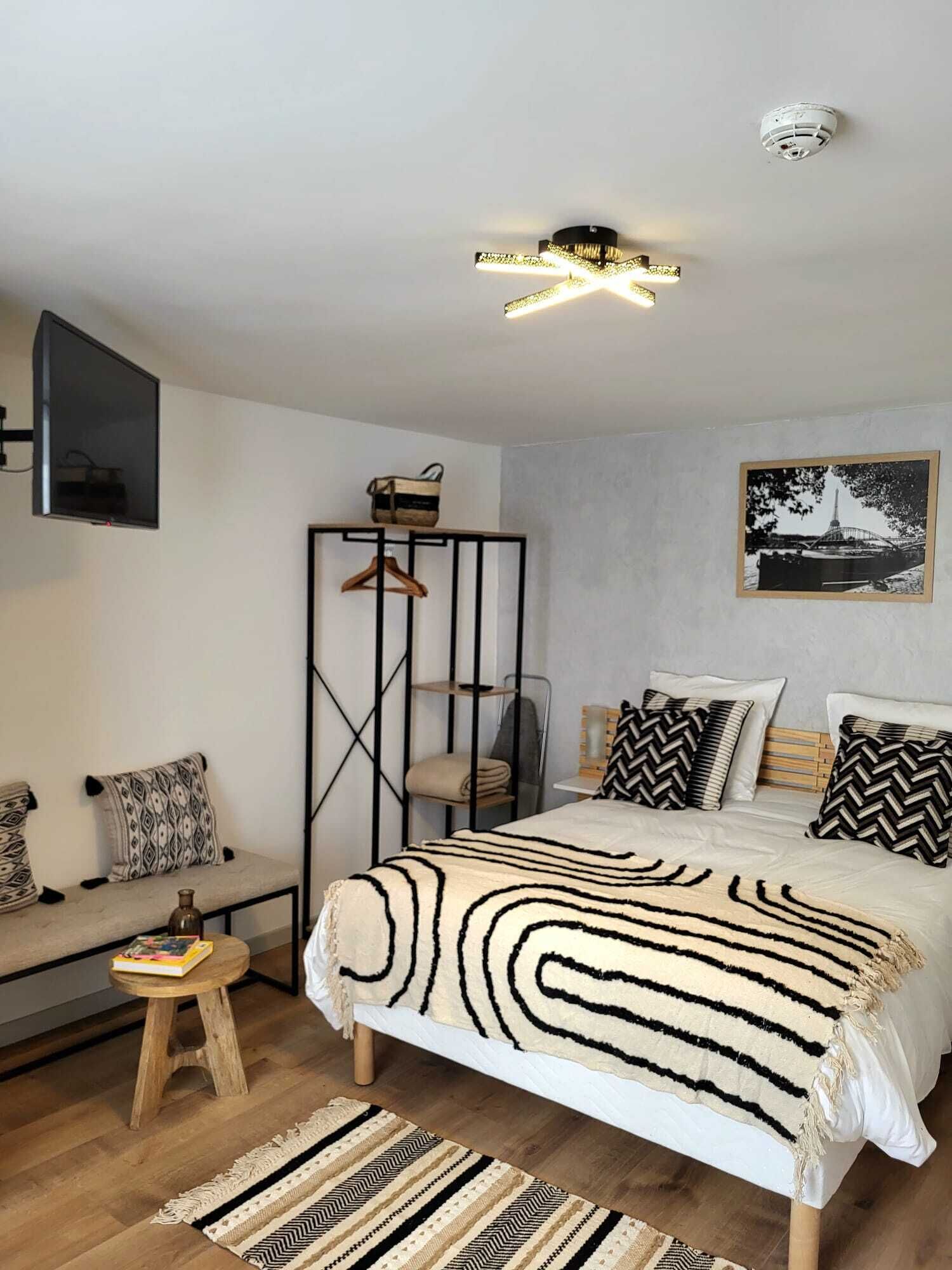 A modern bedroom with a bed, a hanging TV, a wardrobe, and a framed picture on the wall.