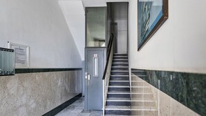 A hallway with a checkered floor, a staircase, and a door with a no-smoking sign.