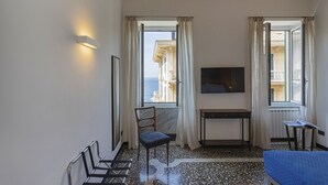 A hotel room with a large window, a flat-screen TV, a small table, a chair, and a bed.