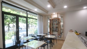 Un restaurante con una larga barra de mármol, sillas negras y una vitrina de vinos.