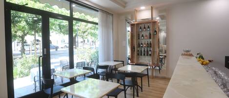 Ein Restaurant mit einer langen Marmor-Theke, schwarzen Stühlen und einer Weinauslage.