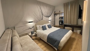 Una habitación de hotel moderna con una cama grande, mesitas de noche, un escritorio y un armario.