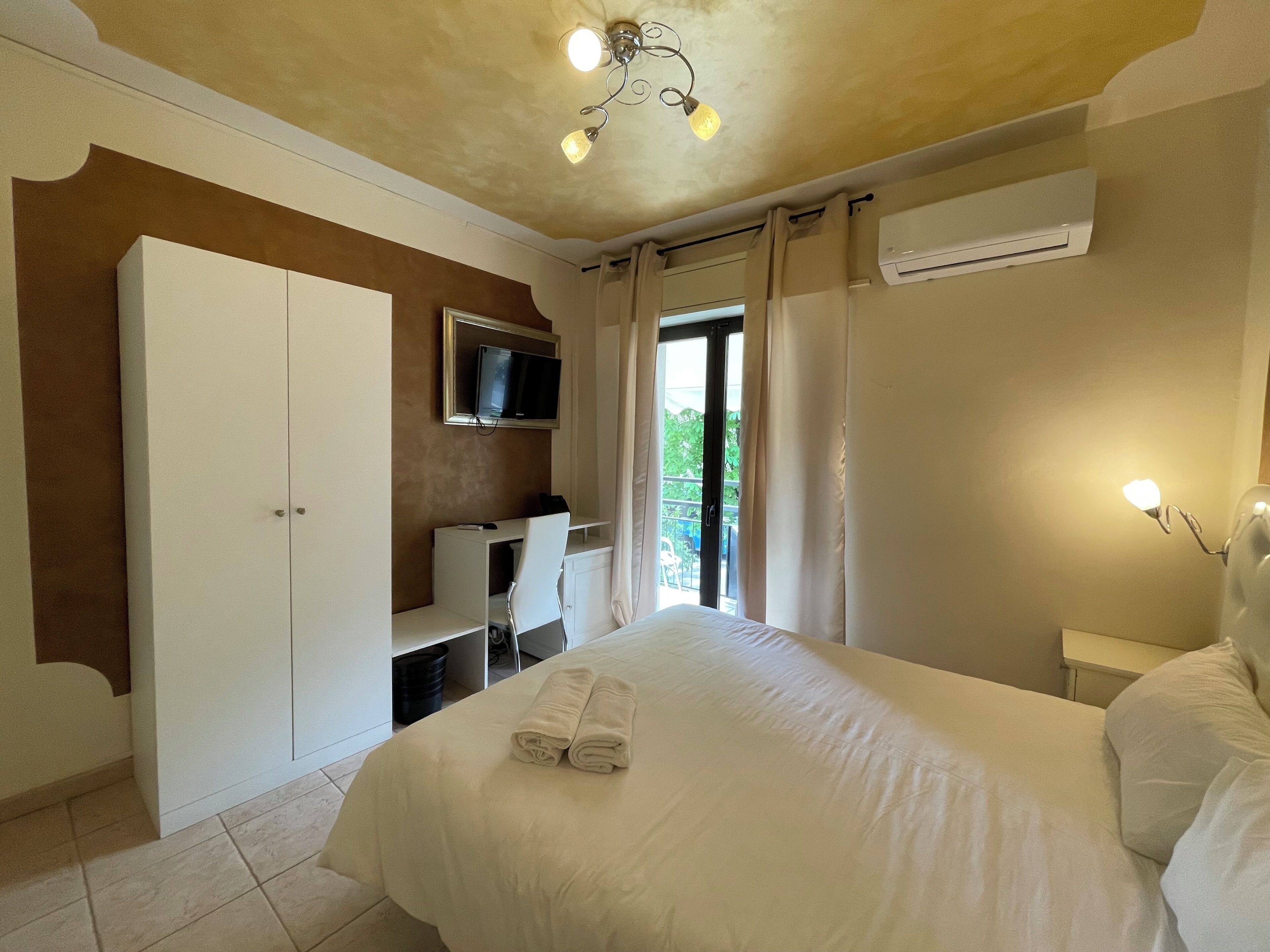 Une chambre à coucher comprenant un lit, un bureau, un téléviseur et un appareil de climatisation.