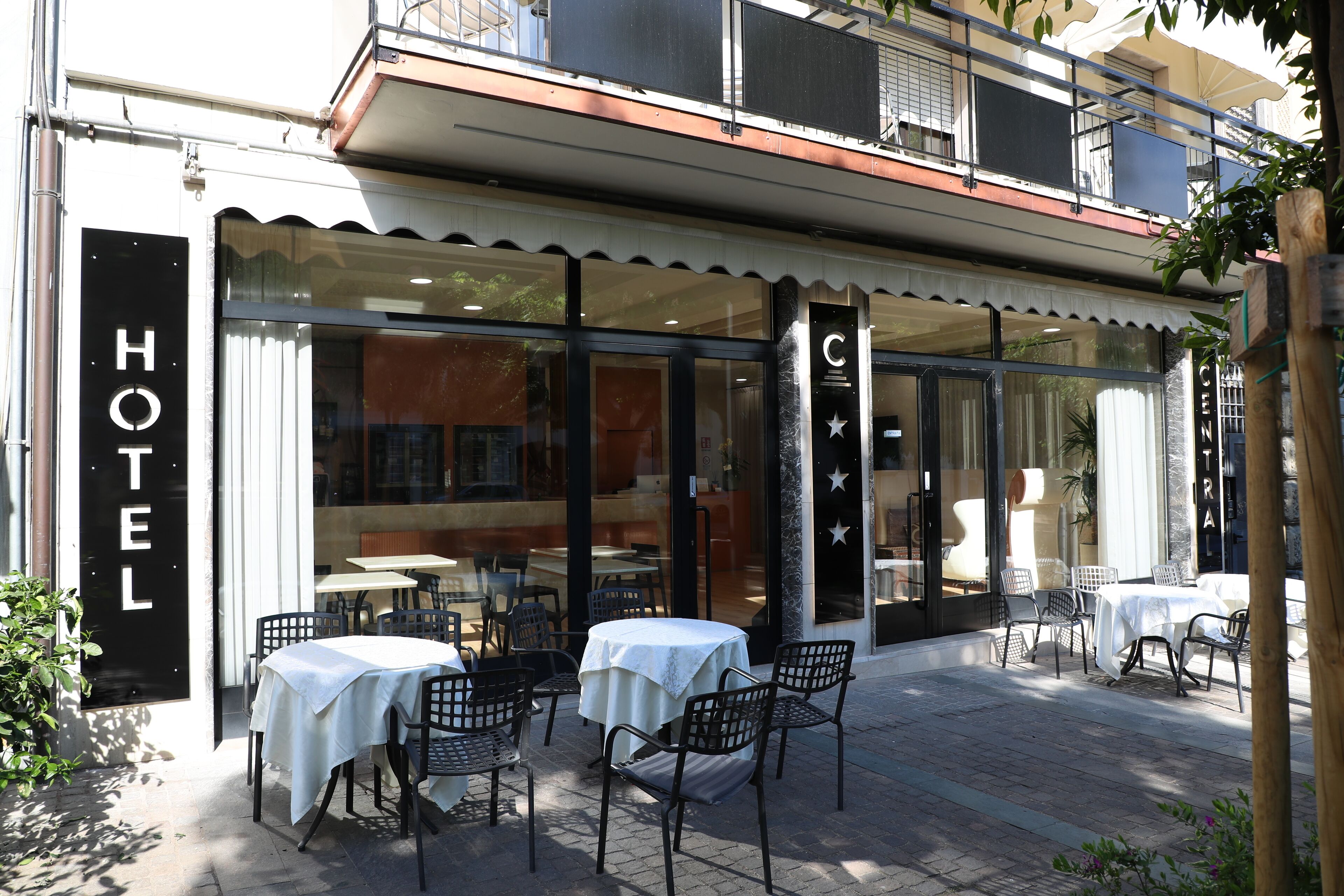 A hotel exterior with outdoor seating and a clear view of the interior through large windows.