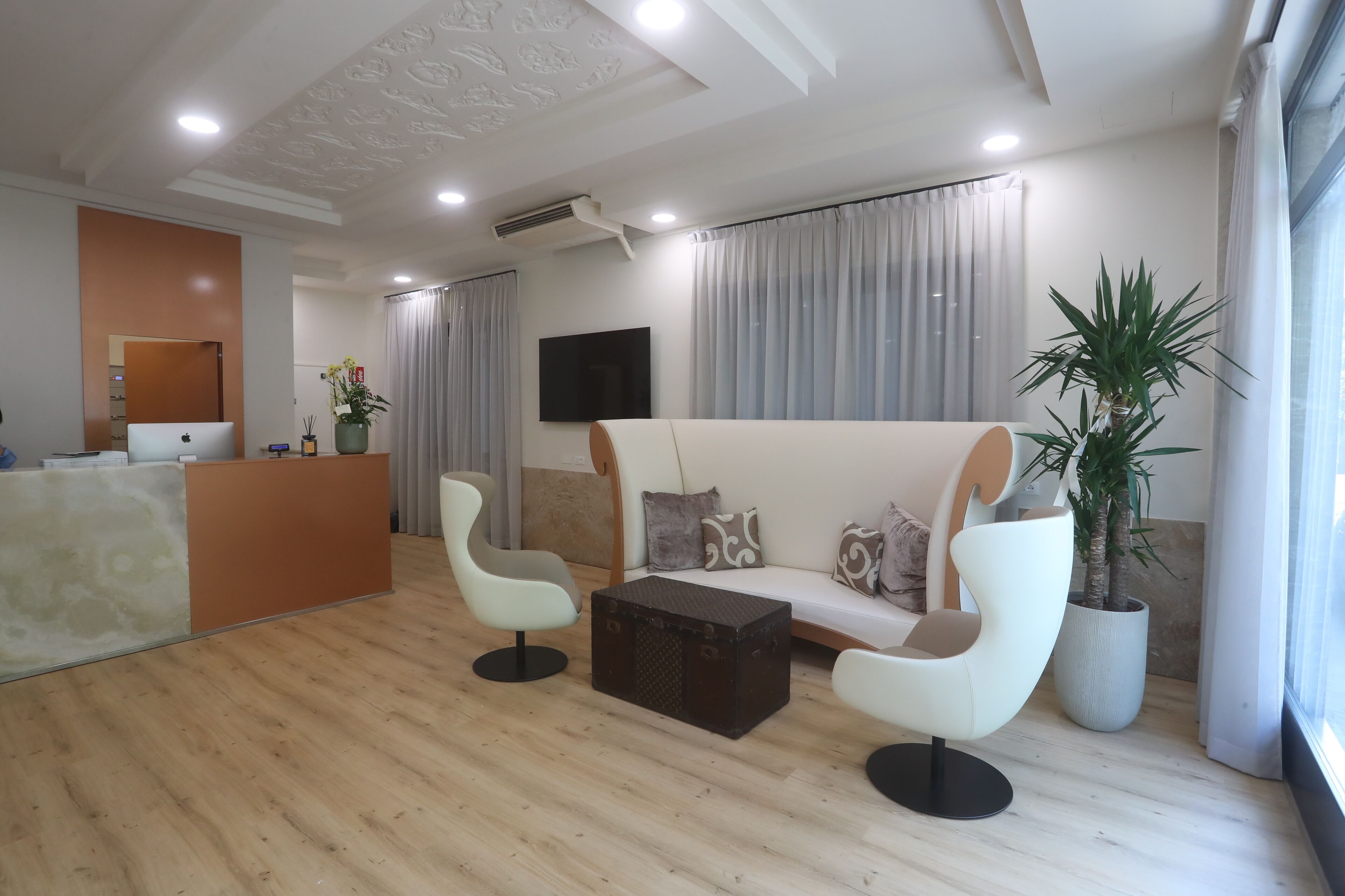 Una sala de estar moderna con un sofá, dos sillones, una mesita de centro y un mostrador de recepción.