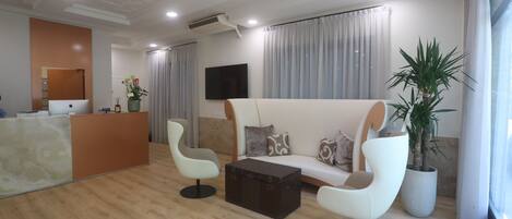 A modern living room with a sofa, two armchairs, a coffee table, and a reception desk.