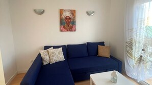 A modern living room with a blue sectional sofa, a white coffee table, and a painting on the wall.