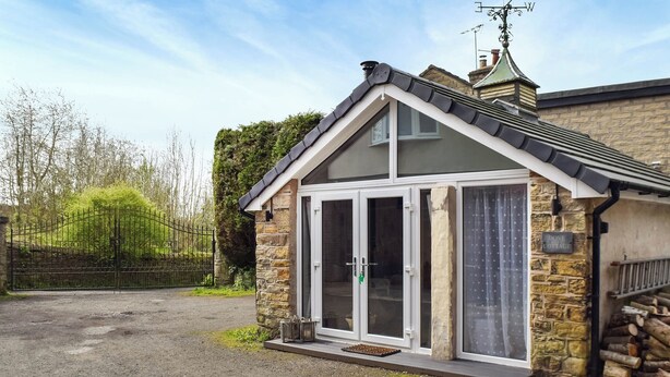 Ein Cottage mit Steinverkleidung, einem Ziegeldach und einem großen Eingang mit Glasdoor.